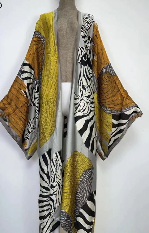 A long open-front kimono-style cardigan draped on a mannequin torso, featuring a bold animal print with zebra stripes and tiger-like markings in yellow, black, white, and gray.